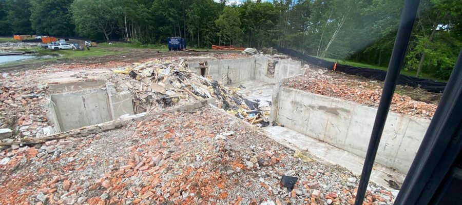 Foundation of house remaining. Exterior brick scattered on ground.